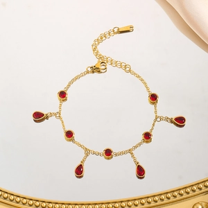Detail of gold titanium steel bracelet with red zircon droplets and lobster clasp