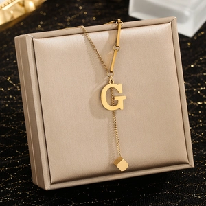 Detail of gold letter G pendant necklace with cubic tassel on a luxury jewelry box