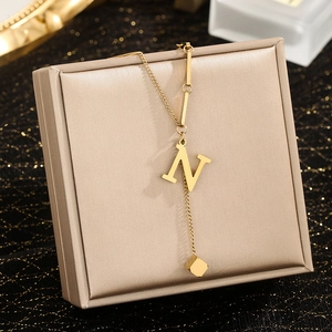Close-up of gold stainless steel necklace with initial N pendant on jewelry box