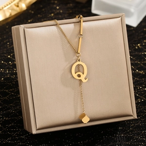 Macro detail of gold letter Q pendant with tassel cube on elegant jewelry box