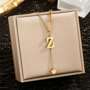 Macro detail of gold letter Z pendant necklace with cube charm on a jewelry box