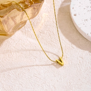 Nahaufnahme der goldenen Buchstabe V Kette auf einer fein strukturierten Steinfläche