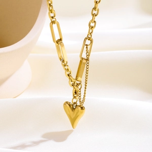 Detalle de collar de capas con colgante de corazón dorado sobre fondo textil
