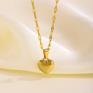 Primer plano del colgante de corazón dorado pulido con cadena de eslabones en seda