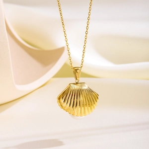 Close-up of golden shell pendant with pearl accent on a fine stainless steel chain