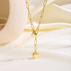 Primer plano de collar dorado con eslabones tipo clip y colgante de corazón en relieve