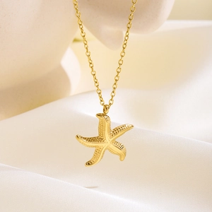 Detailed view of a golden starfish pendant necklace with textured finish on white silk