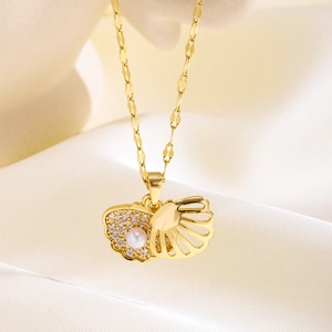 Detailed close-up of 18k gold shell necklace with pavé zircon and a single white pearl