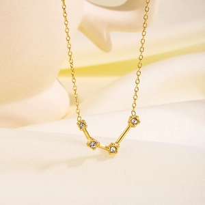 Elegante goldene Sternbild-Halskette mit Kristallakzenten auf weißem Seidenhintergrund