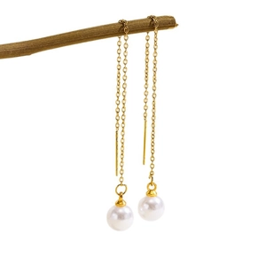 Elegant gold drop earrings with long tassels and white pearls hanging on a natural branch