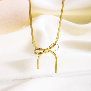 Minimalistische goldene Schlangenkette mit einzigartigem Schleifenanhänger auf weißer Seide