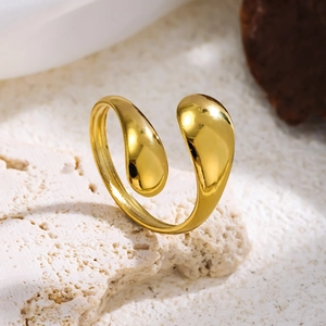 Nahaufnahme eines 18K vergoldeten offenen Rings in Tropfenform auf strukturiertem Stein