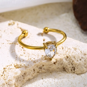 Detail eines 18K vergoldeten offenen Rings mit Zirkonia und Kugeln auf Steinstruktur
