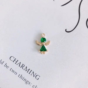 Detailed macro view of an angel-shaped pendant with green zircon and gold plating