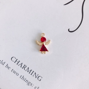 Macro shot of an angel charm featuring faceted red crystal and golden wings on a card