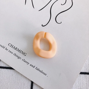 Detalle de anillo abierto de resina mate naranja con forma cuadrada irregular minimalista