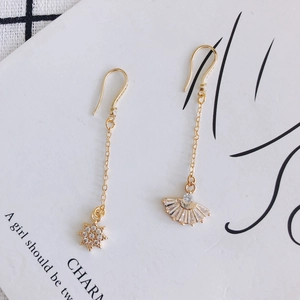 Detailed view of asymmetric gold-plated star and fan drop earrings with zircon