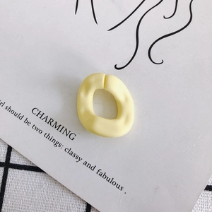 Detalle de un dije cuadrado irregular de resina amarillo mate con textura de martilleo