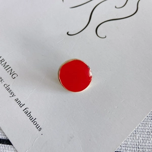 Détail macro d'un élément de boucle d'oreille en émail rouge et cadre doré irrégulier