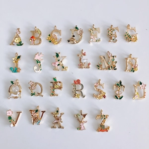 Flache Ansicht bunter Emaille-Buchstabenanhänger mit Blumen auf Goldlegierung
