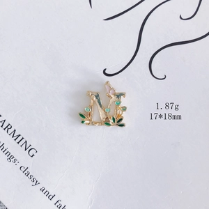Detail eines goldenen M-Emaille-Anhängers mit grünen Blättern und rosa Schmetterling