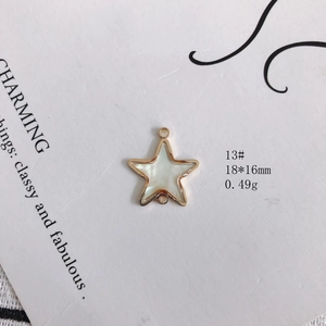 Détail macro d'un pendentif étoile 18x16mm avec cadre doré et insert en nacre blanche