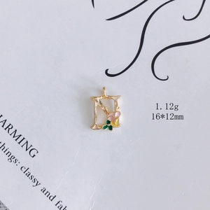 Detail eines goldenen Emaille-Buchstaben N mit rosa und gelben Blumen, 16x12mm