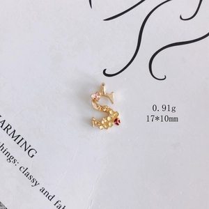 Detailansicht eines goldenen S-Anhängers mit rosa und gelben Emaille-Blumendetails