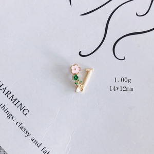 Detailansicht der rosa Emaille-Blume und grünen Blätter am goldenen Anhänger Buchstabe V