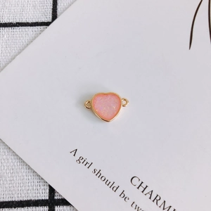 Close-up of pink resin heart pendant with gold rim and double rings for DIY jewelry