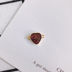 Close-up of heart-shaped glitter charms with gold edges and purple resin for DIY jewelry