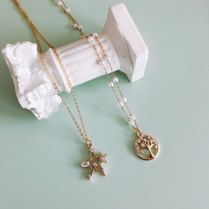 Gold plated necklaces with star and tree of life charms on white decorative pillars