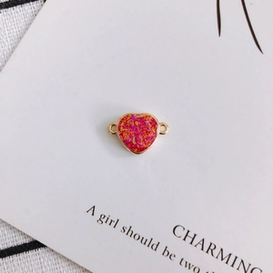 Detail of magenta resin heart pendant with gold metal frame and dual loops for DIY jewelry