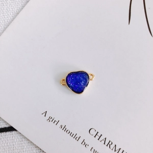 Macro detail of heart-shaped dark blue resin charm with gold-plated metal borders