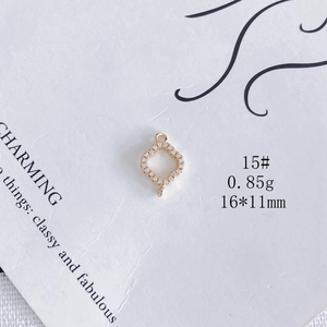 Vue macro d'un pendentif trèfle évidé plaqué or avec zircons et deux anneaux de fixation