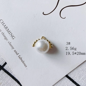 Detail of a 19.5x20mm round pearl pendant with a gold rim and rhinestone accents