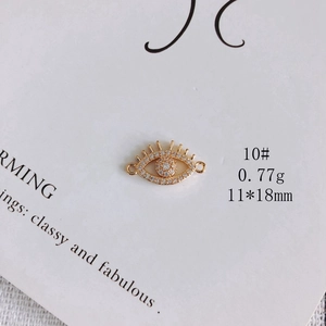 Macro view of gold-plated eye pendant with white zircon inlays and link loops