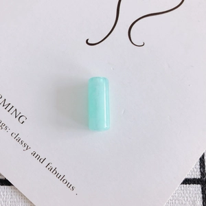 Dettaglio di una perla cilindrica in resina verde menta con finitura lucida per gioielli DIY