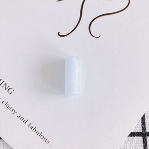 Primo piano di una perla cilindrica in resina azzurra su carta decorativa per gioielli fai da te