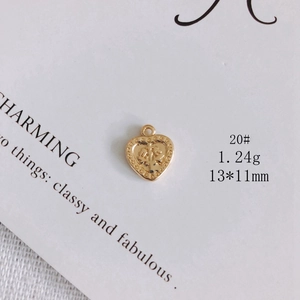 Macro view of heart-shaped gold-plated pendant with floral relief patterns, 13x11mm size