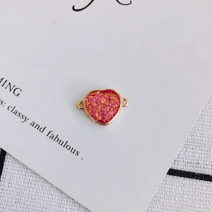Detail view of heart-shaped gold-plated connector with sparkling pink glitter for DIY jewelry