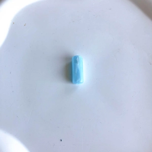 Dettaglio di perla cilindrica in resina azzurra marmorizzata per creazione gioielli