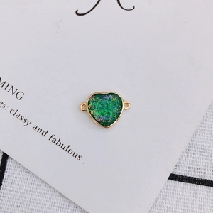 Detail of heart-shaped green resin pendant with gold copper trim and dual side hooks
