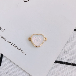 Macro detail of heart-shaped gold-rimmed charm with white glitter for DIY jewelry making