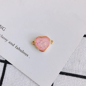 Macro shot of heart-shaped pink glitter resin charm with gold plated double loop connectors