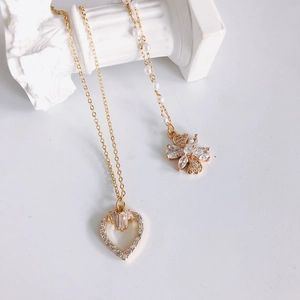 Golden heart and clover necklace set with cubic zirconia and pearls on elegant white background