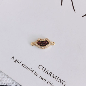Detail of lip-shaped gold pendant with cubic zirconia inlay and red glitter finish