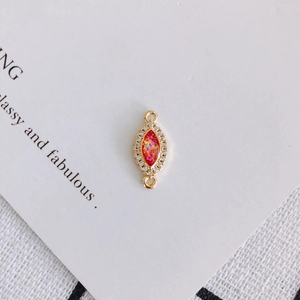 Macro view of marquise resin charm with red opal finish and gold plated zircon frame