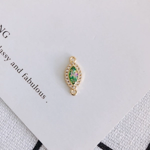 Detailed view of gold-rimmed marquise resin pendant with white zircon inlays and dual loops