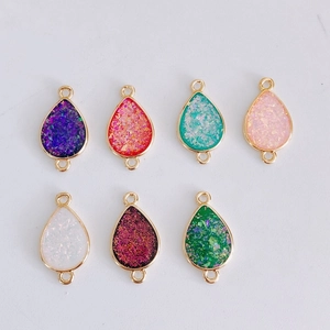 Close-up of 7 colorful teardrop pendants with gold frames and glittery resin texture